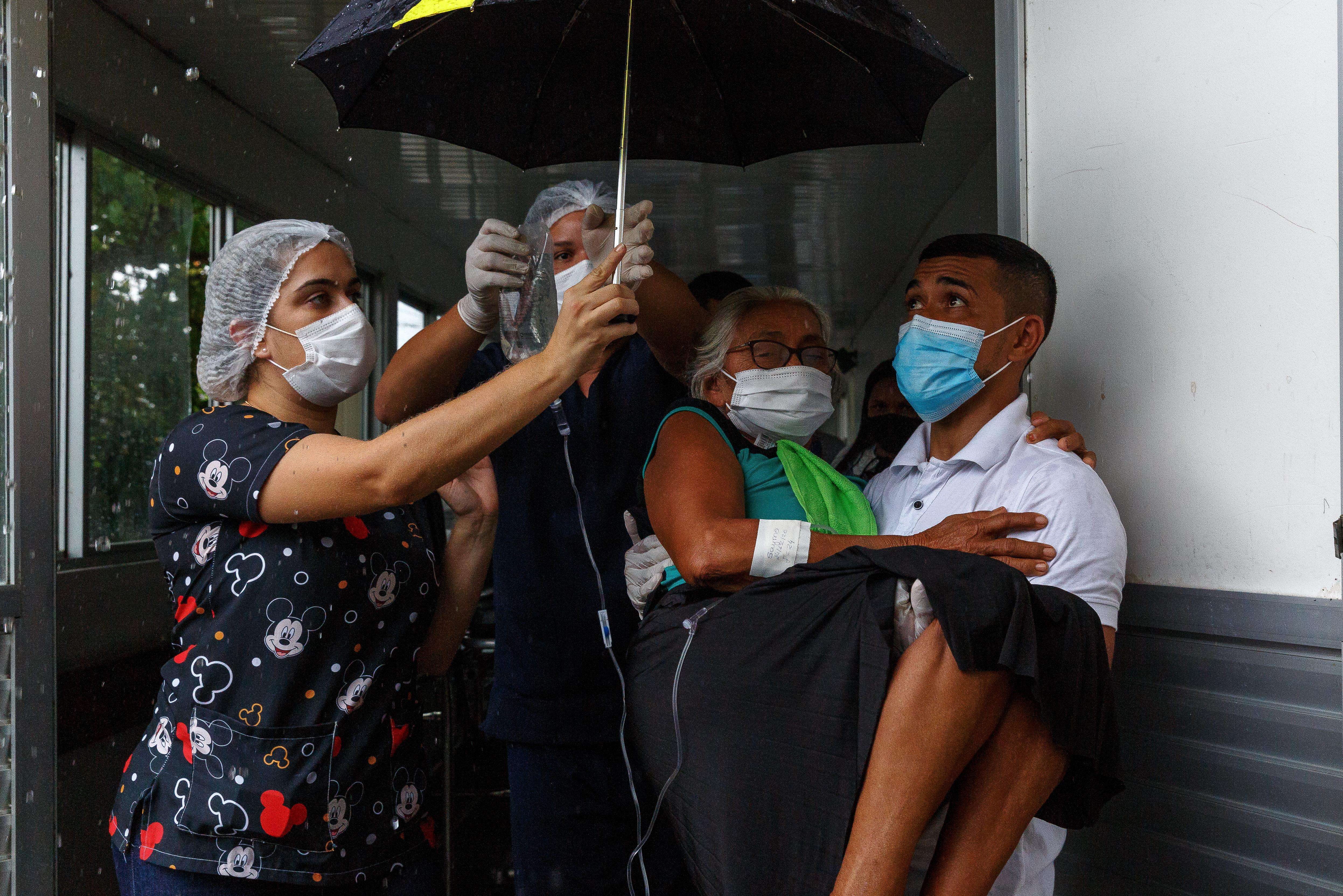 Medical team holding a woman outside and under an umbrella