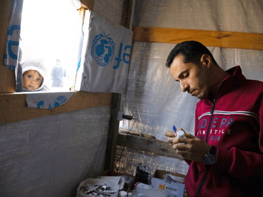 A man looks at notes as a child looks through the window of a clinic in Gaza.