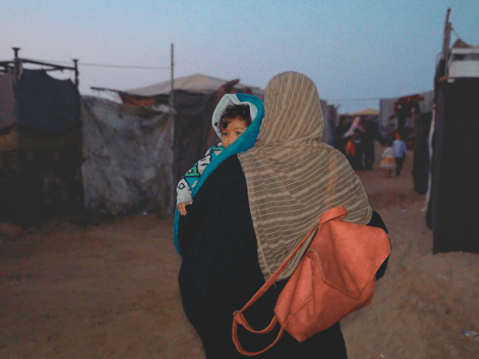 A displaced Palestinian woman and her child in a tented camp in Gaza.