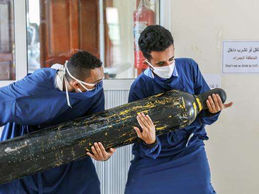 Workers carry an oxygen cylinder to the intensive care unit.