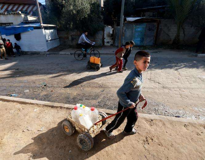 A Palestinian child fetches water from a distribution point in Rafah, Gaza.