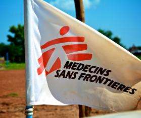 White flag with red logo of Doctors Without Borders/Médecins Sans Frontières (MSF) against sunny blue sky